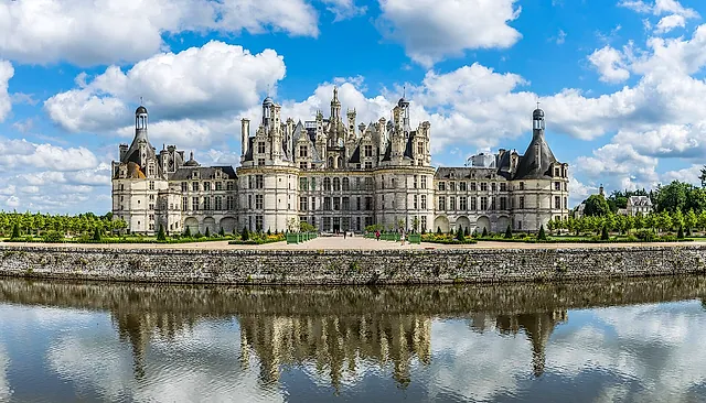 La facciata nord-ovest del castello di Chambord riflessa nel canale sotto un cielo azzurro