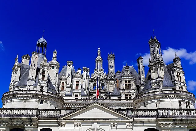 La linea dei tetti del castello di Chambord con torri, lanterne e camini contro un cielo blu intenso