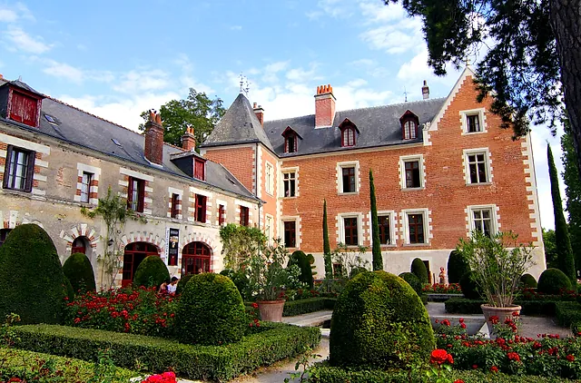 Il maniero in mattoni e pietra del Clos Lucé visto dal giardino con siepi di bosso e rose